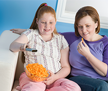 mom and daughter eating junk food and watching tv