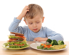 boy scratching his head looking at plate of veggies and huge sandwich