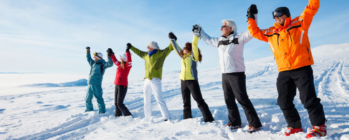 group of people raising hands together in the snow