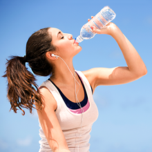 girl with headphones drinking from bottle of water