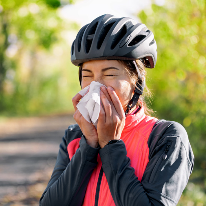woman with bike helmet sneezing