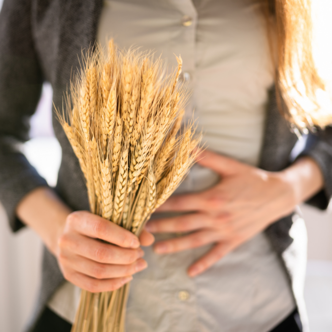 Woman with a stomach ache holding wheat