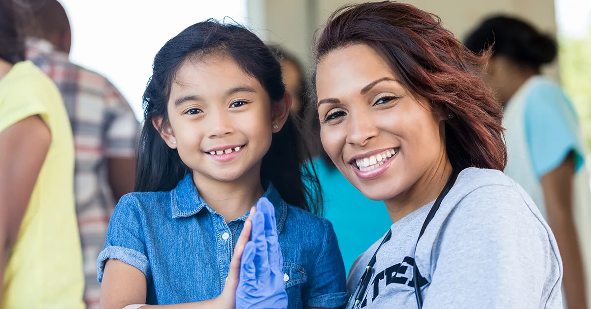 A female medical professional smiles with at toddler