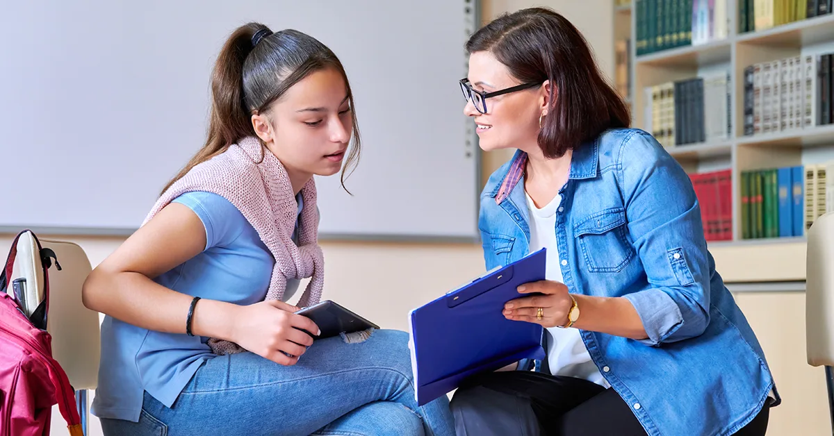 A teacher shows a notebook to a student