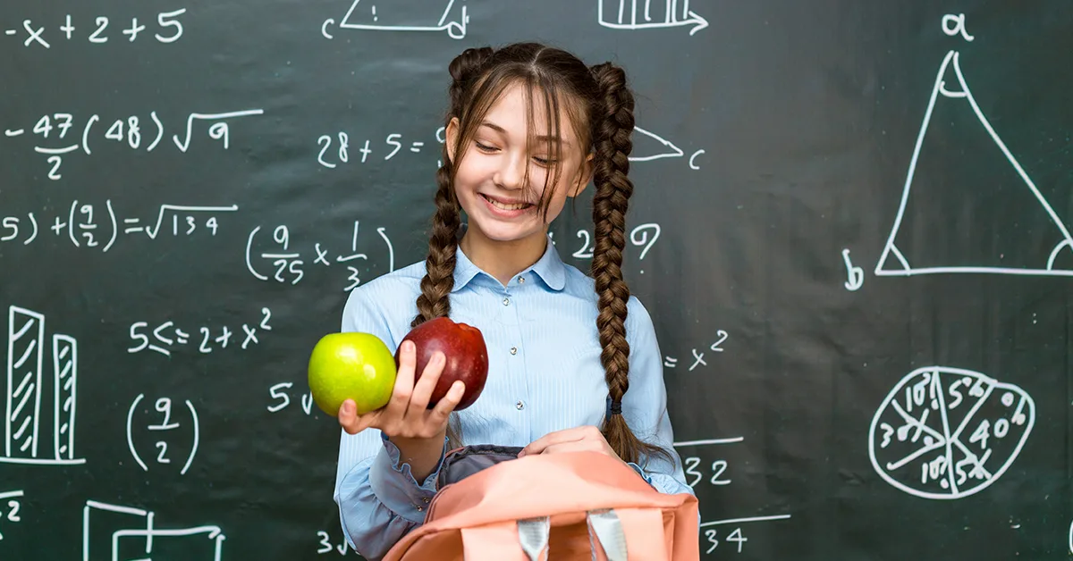 A teenage girl in braids smiles at the fruit she is holding