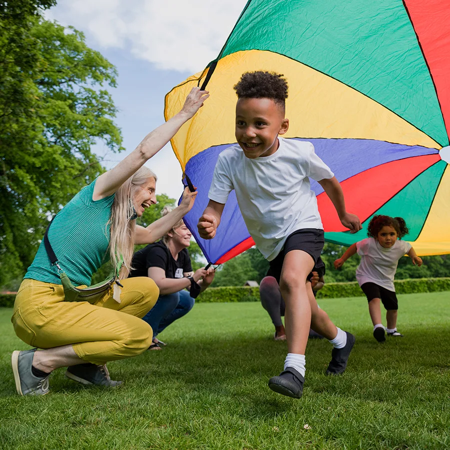 Young kids run under a parachute