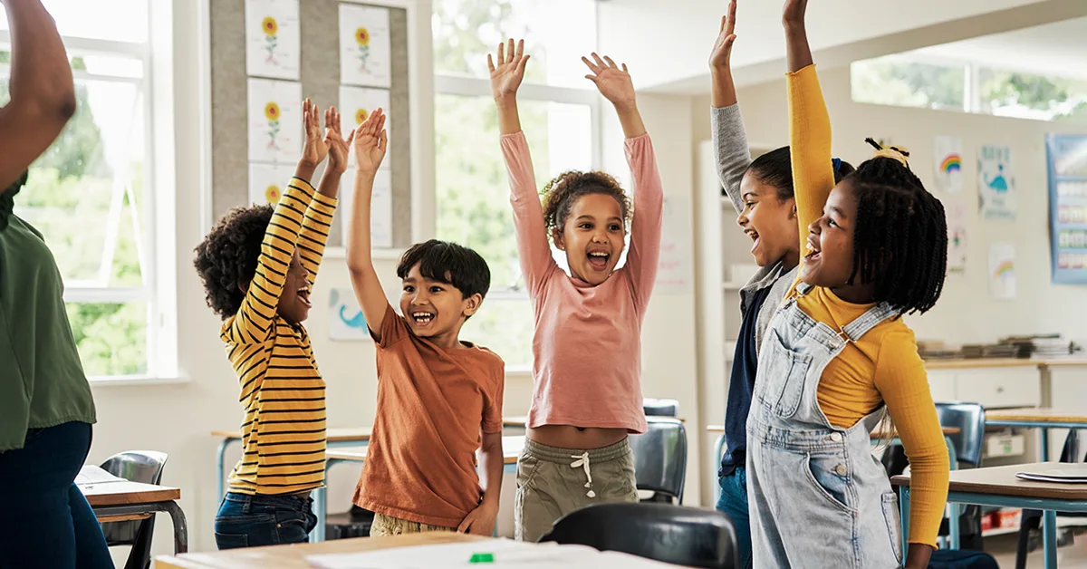 A group of kids cheering in a classroom