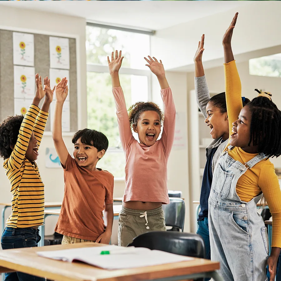 A group of kids cheering in a classroom